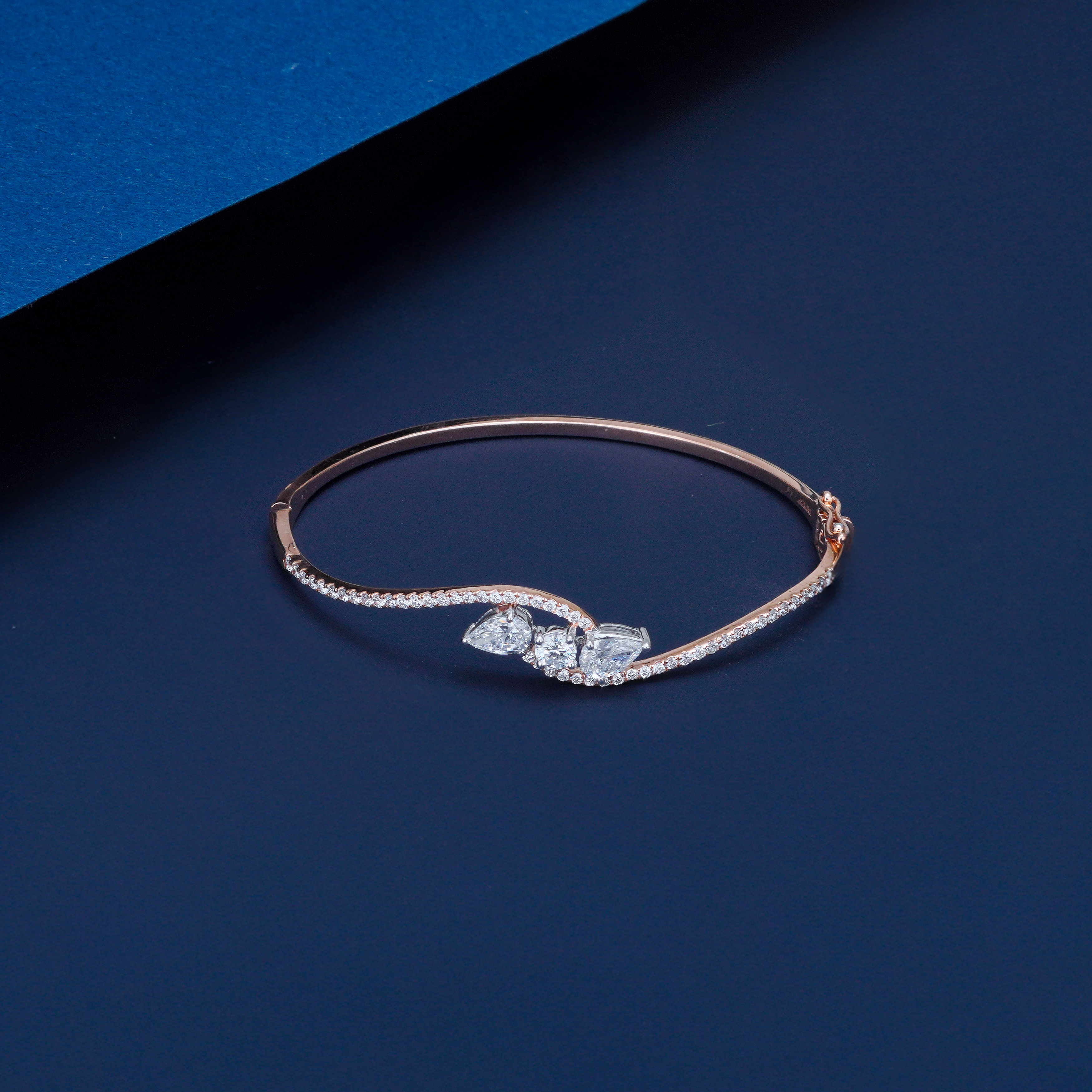 Rose gold bracelet with diamonds on a blue background
