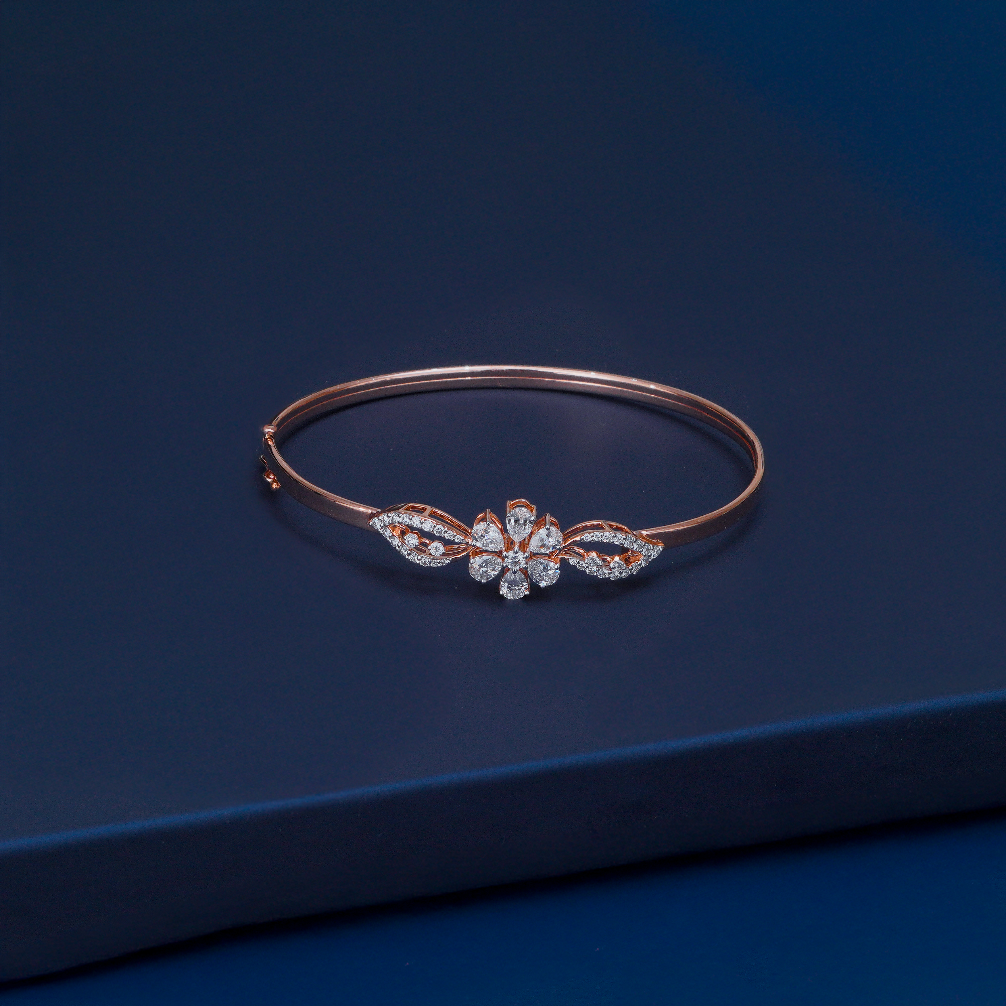 Rose gold bracelet with floral design on a dark blue background