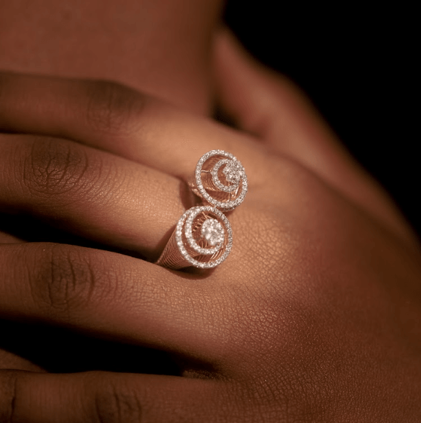 A person wearing two white gold rings on their fingers, with the rings displaying a double roller design.