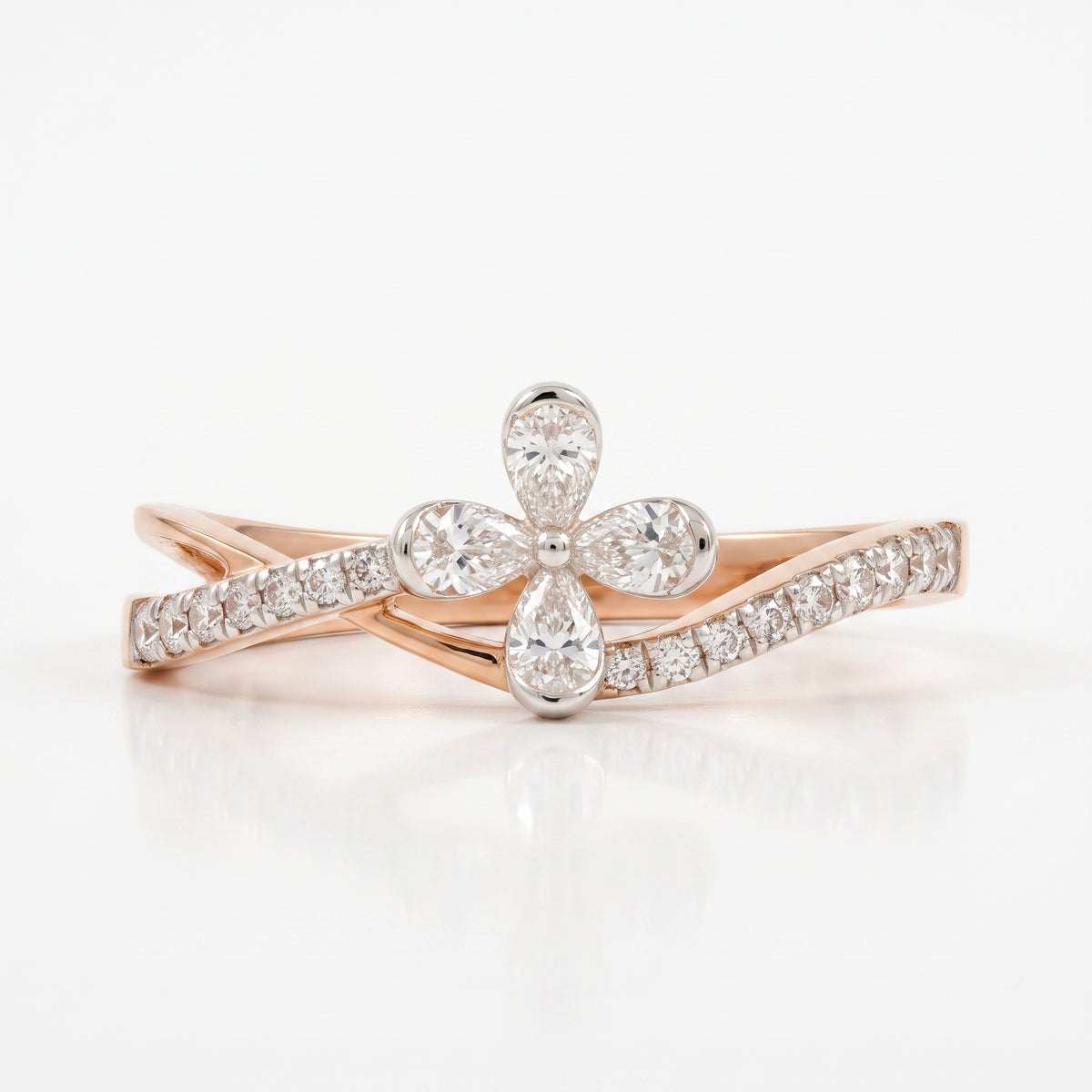 A rose gold ring featuring a central diamond flower motif with four pear-cut diamonds, flanked by two curved bands paved with round diamonds, set against a clean white background.