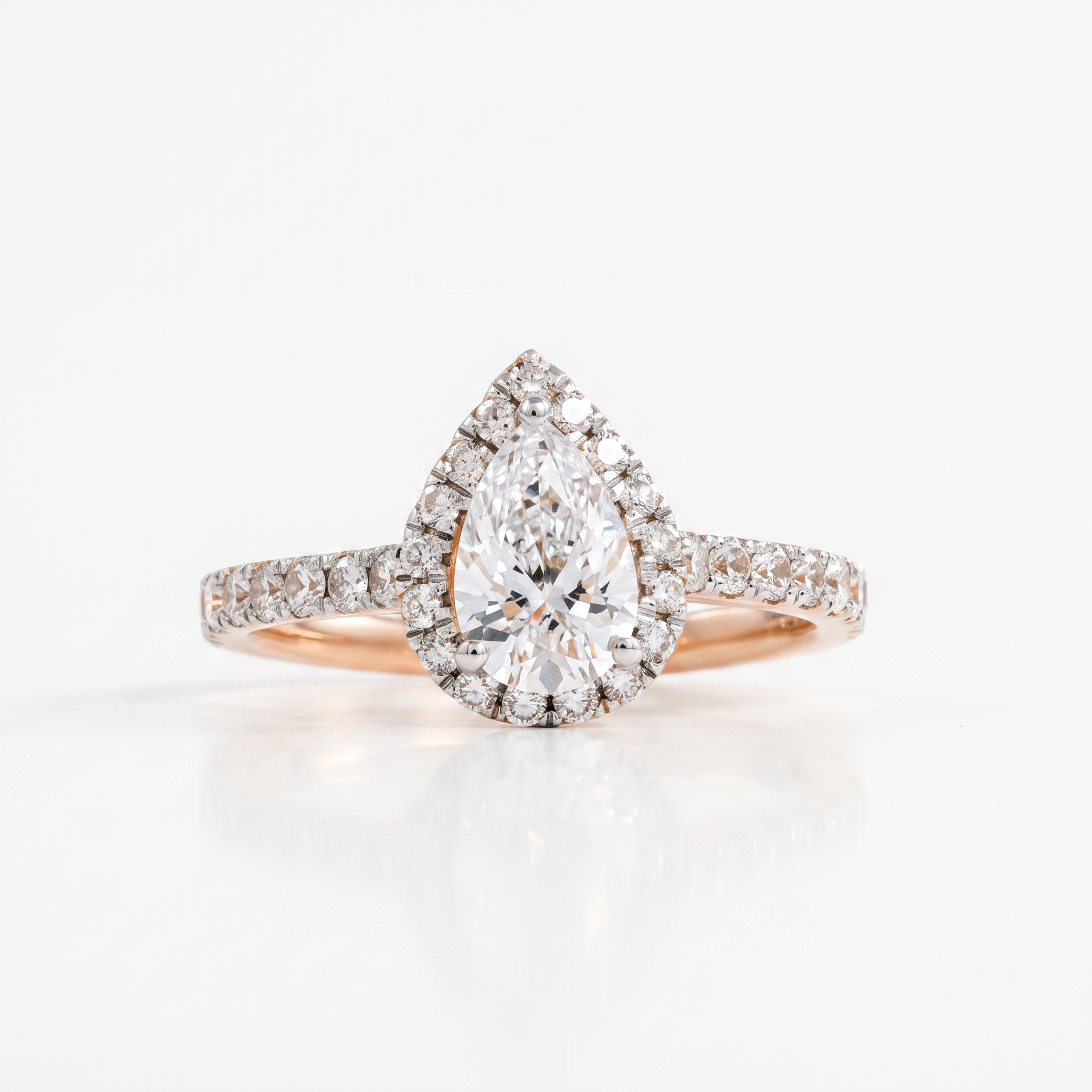 A pear-cut diamond engagement ring with a halo setting and a rose gold band paved with small diamonds, shown on a clean white background with a soft reflection.