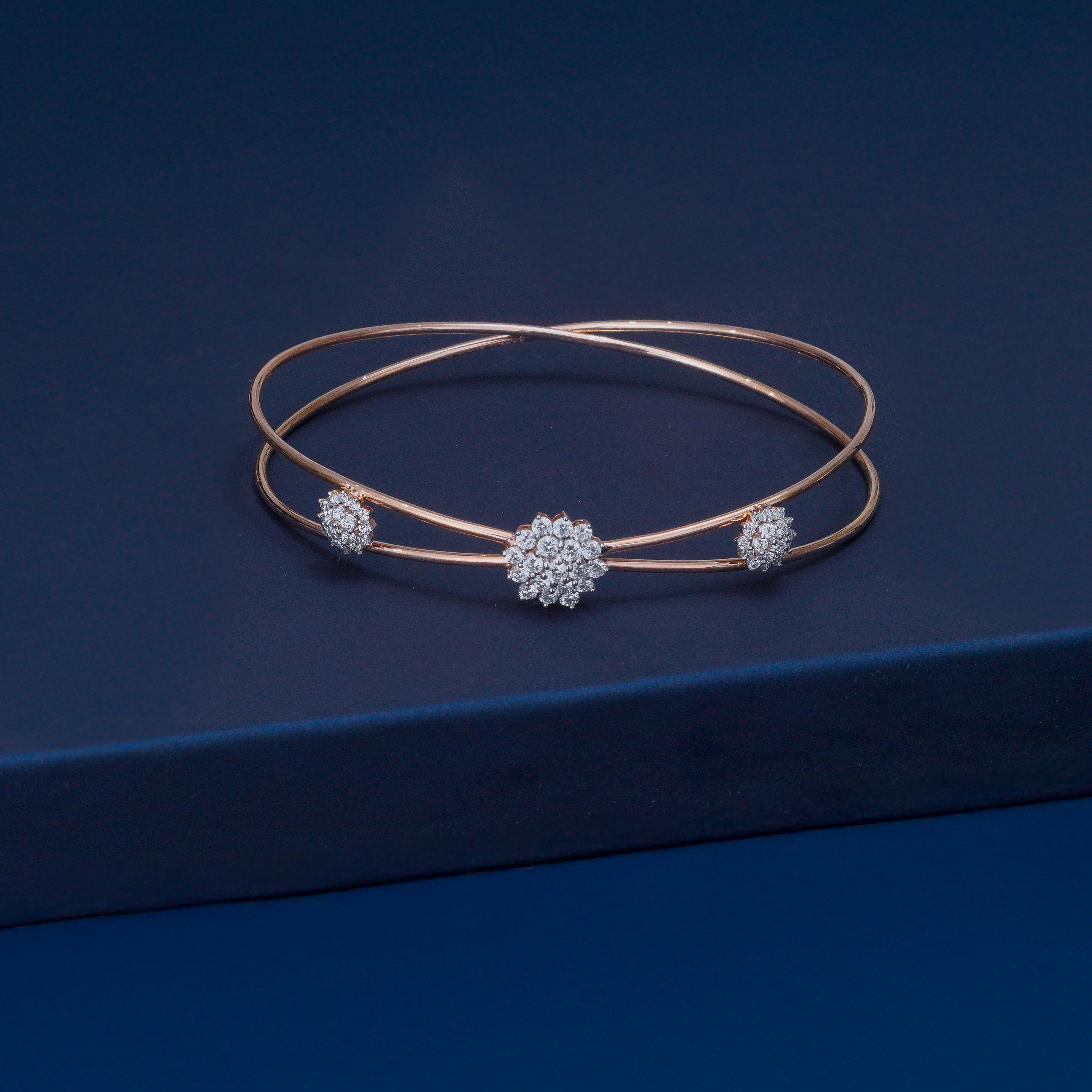 Rose gold bracelet with diamond accents on a dark blue background