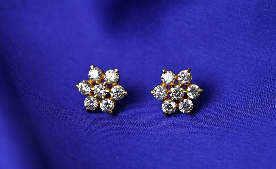 A pair of floral seven-stone stud earrings on blue fabric