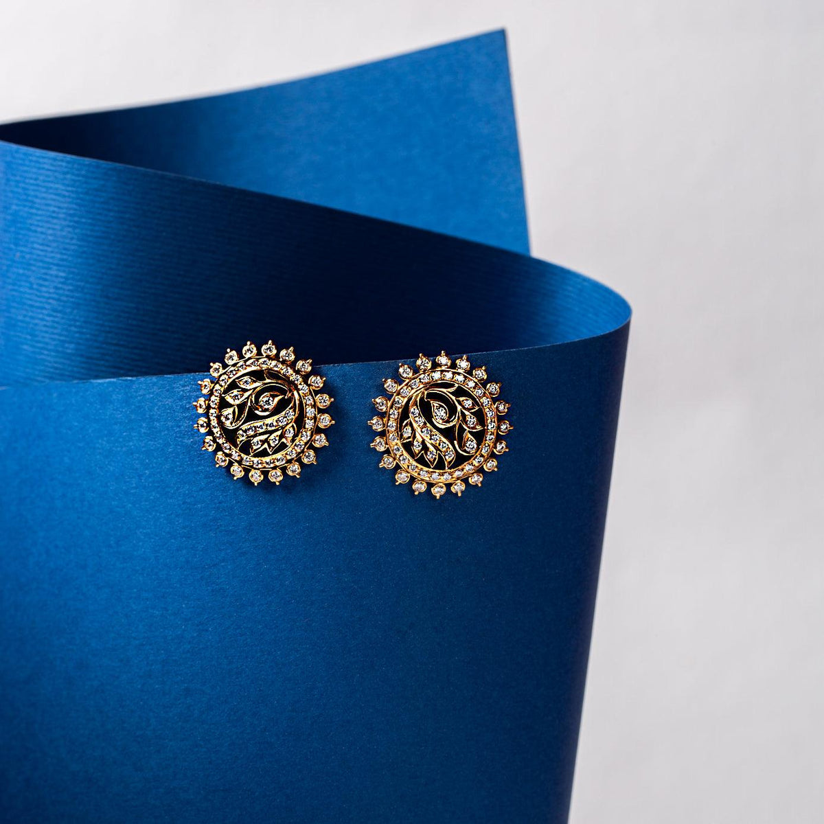 Ornate circular stud earrings on a blue background