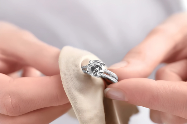 A hand gently cleaning a ring with a soft cloth