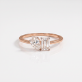 A rose gold ring with a split design featuring a pear-cut diamond on one side and an emerald-cut diamond on the other, set against a clean white background.