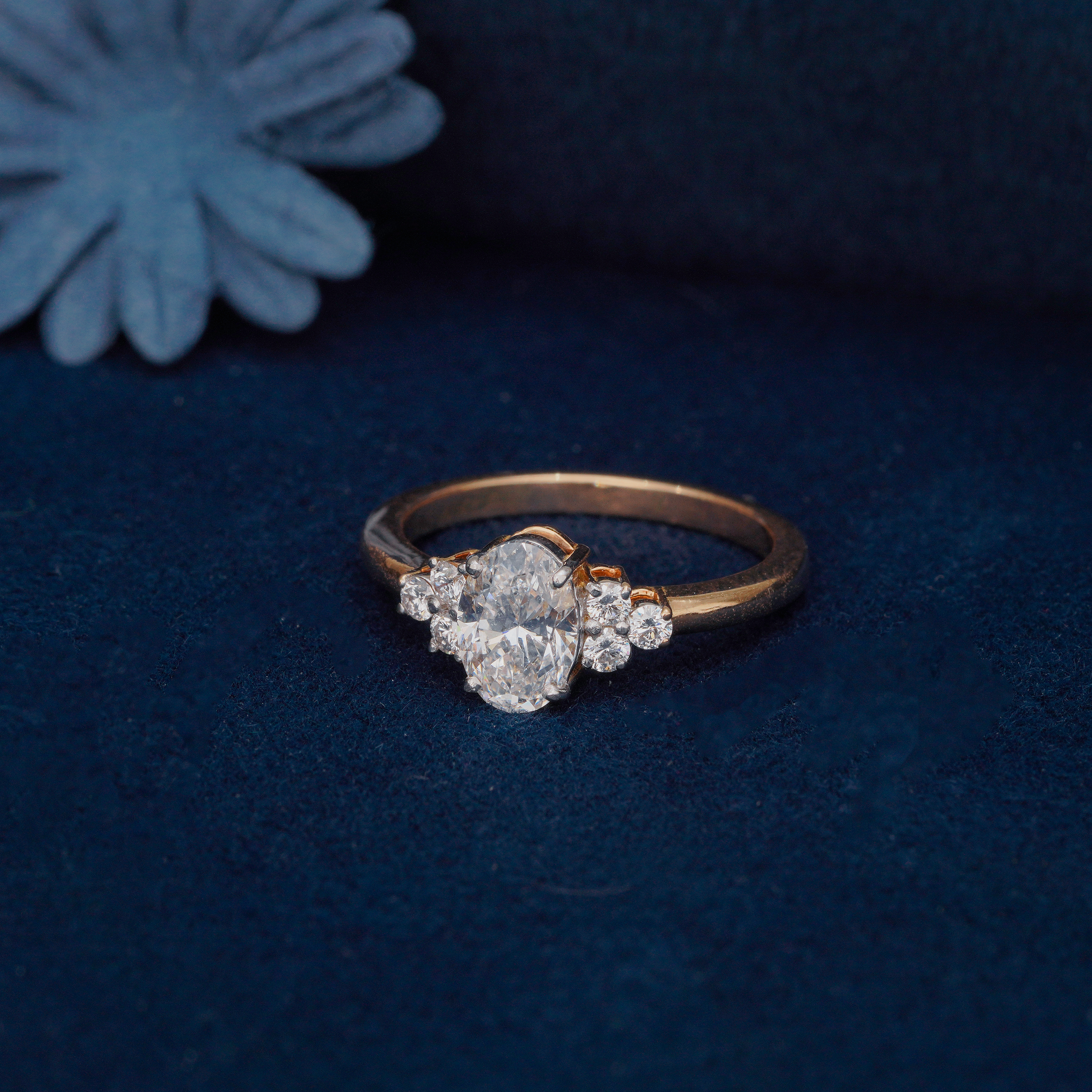 Oval-cut lab diamond engagement ring with trinity side clusters in a polished yellow gold setting.