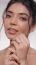 A person showcasing a diamond ring on their finger, with a focus on the ring.