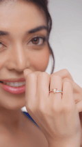 A person is wearing a diamond ring, and the image is focused on the ring and the person's hand holding it, with a blurred background.