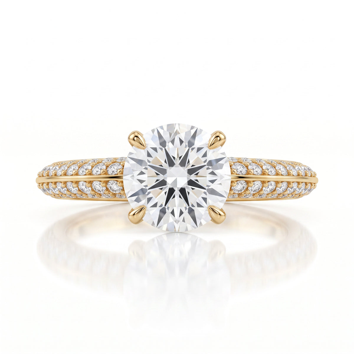A yellow gold engagement ring featuring a large round-cut center diamond and a pavé-set diamond band, shown on a clean white background with a soft reflection.