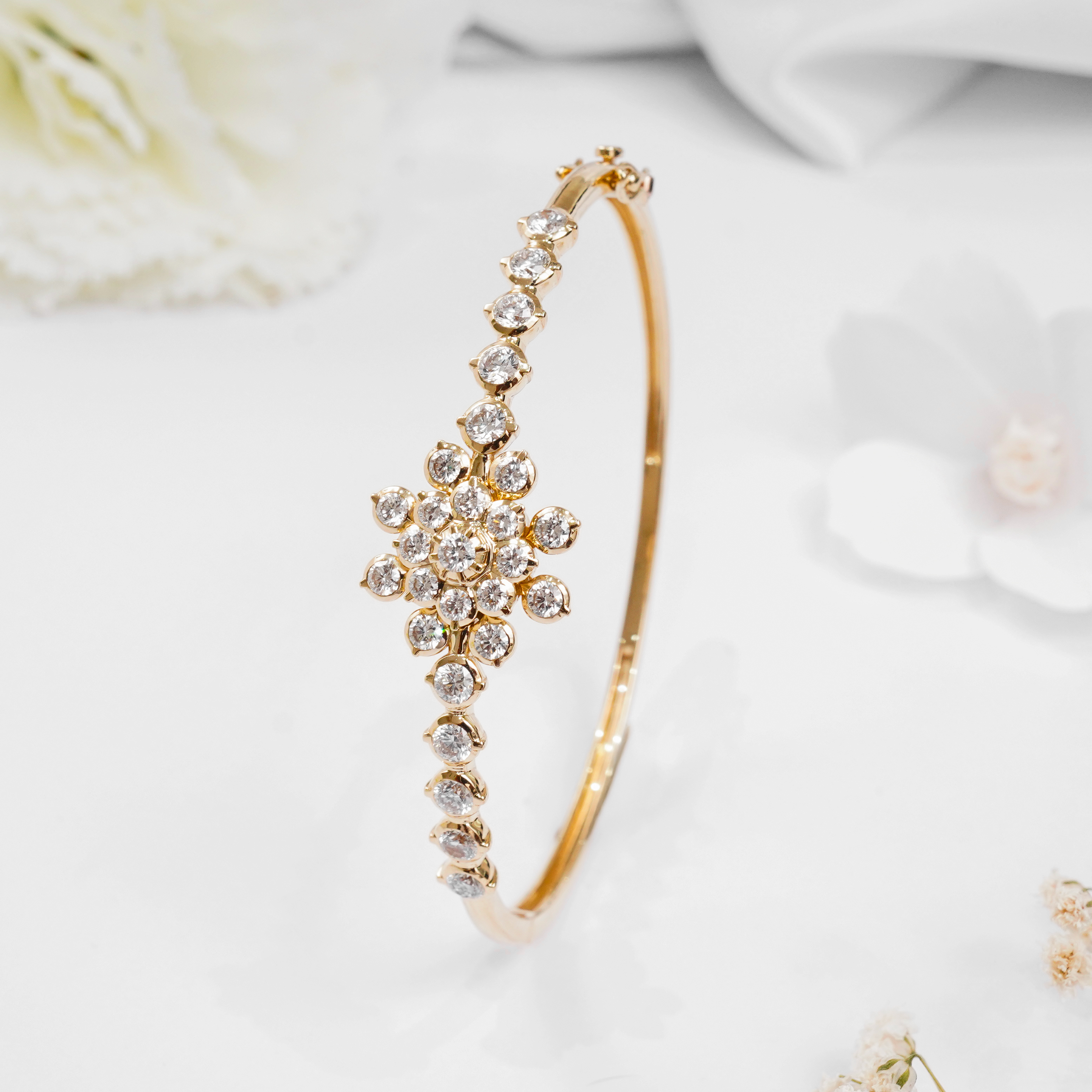 Traditional 14k gold hinged bangle with a central lab diamond floral cluster in a closed setting on white background.