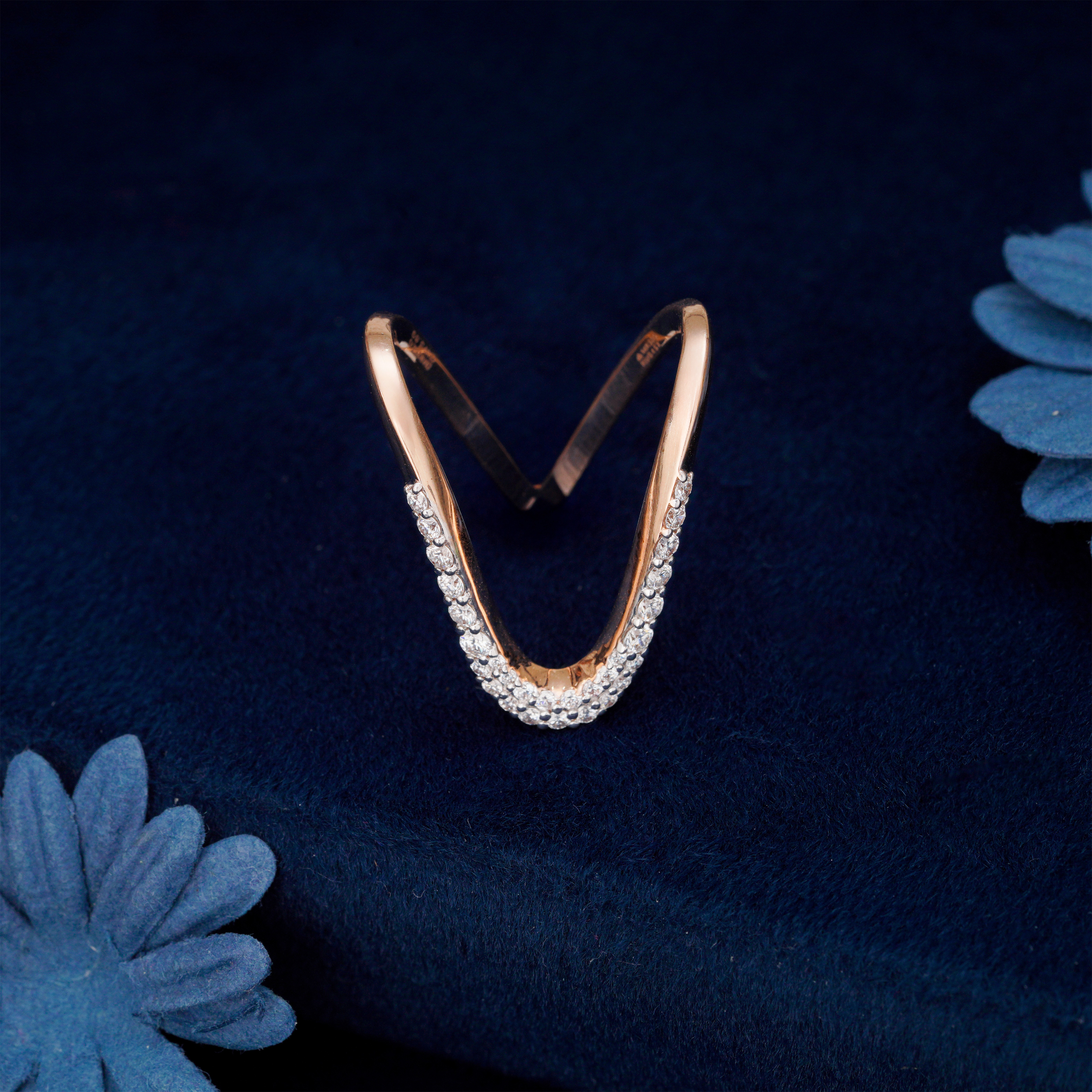 Gold hoop earring with diamonds on a dark blue fabric background. The Vara 18K Rose Gold Diamond Vanki Ring for women