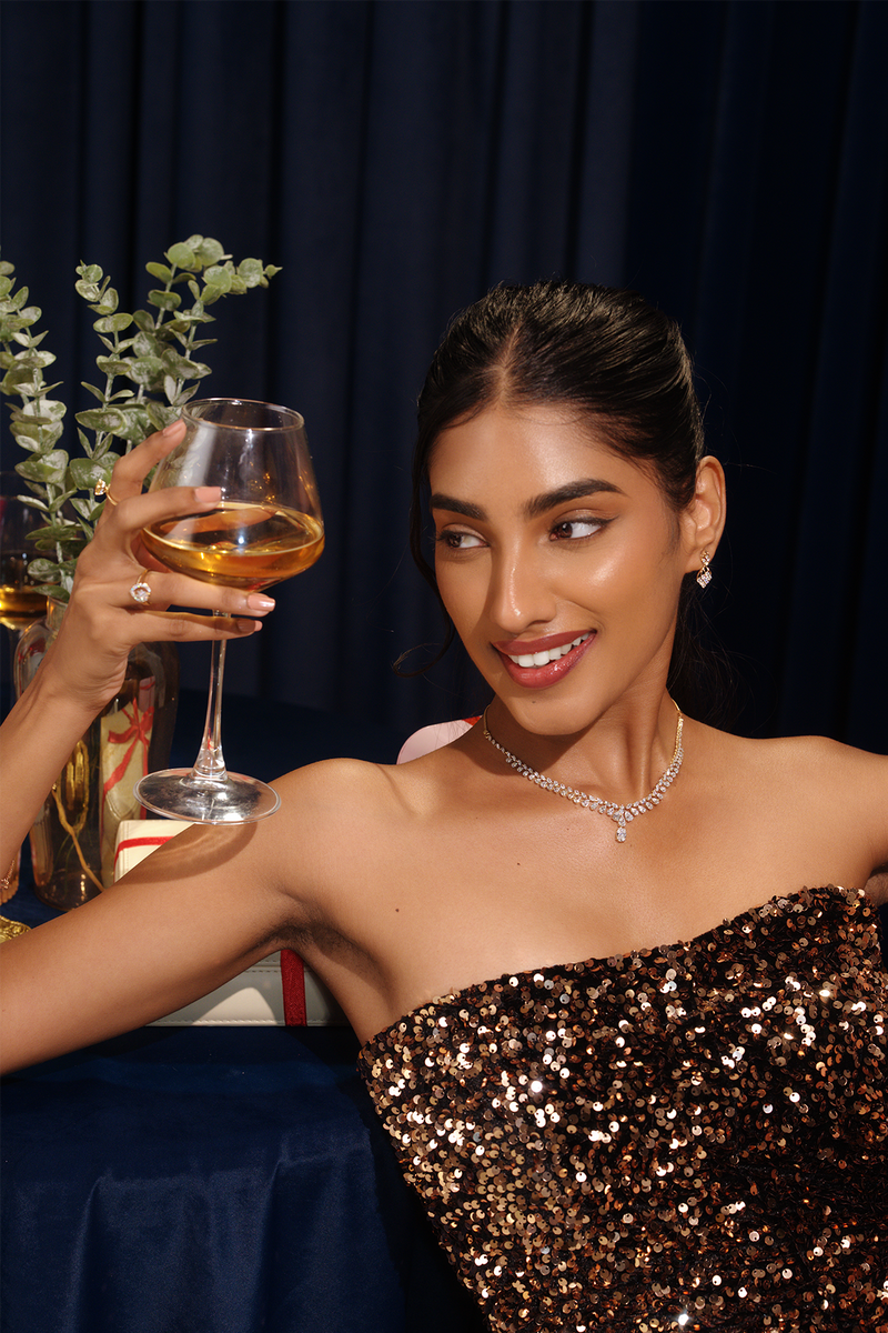 Model wearing jewellery and holding a glass