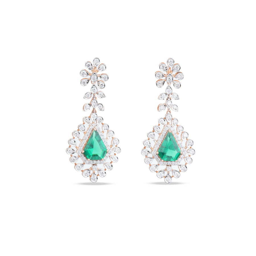 A pair of teardrop-shaped drop earrings featuring a central green emerald-cut stone surrounded by clear pavé stones, with floral studs above, set in a silver-toned metal on a white background.