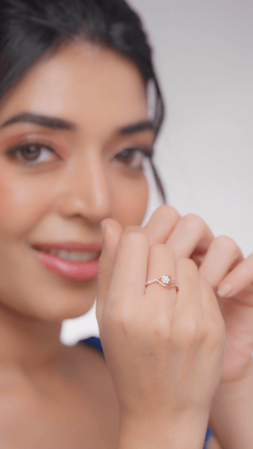 A woman showcasing a diamond ring on her finger, with the ring being the focus of the image.