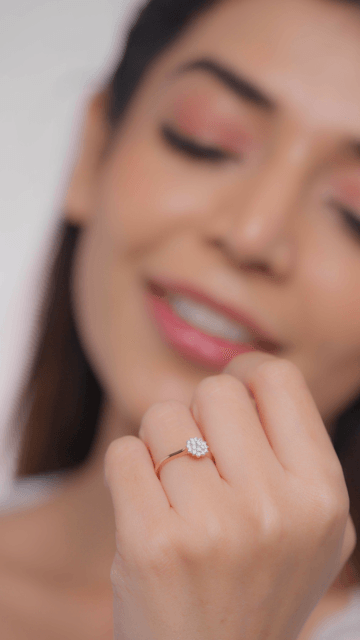 A person is wearing a diamond ring, and the image is focused on their hand holding the ring.