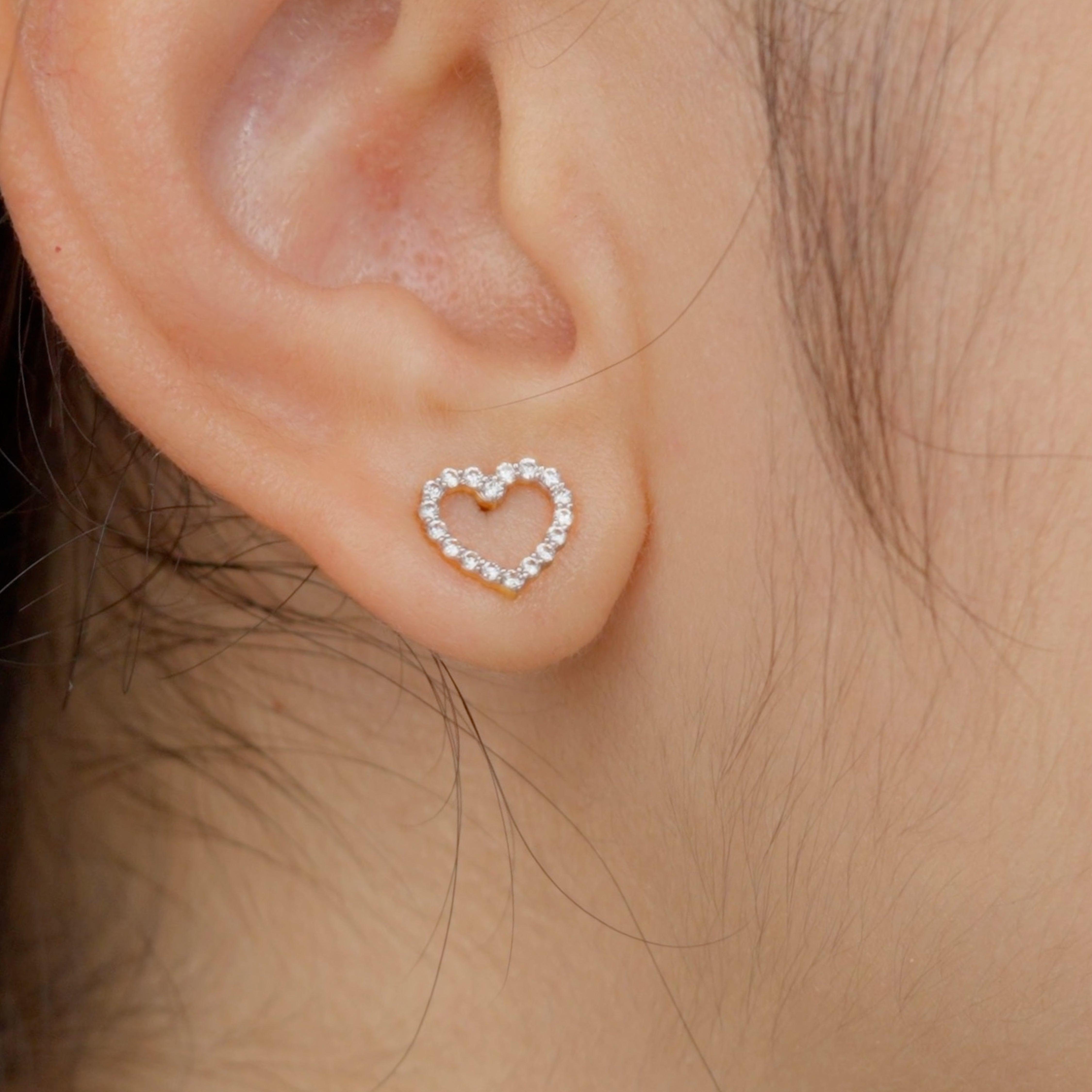A close-up image of a person wearing a heart-shaped diamond earring.